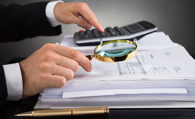 Businessperson Checking Invoice With Magnifying Glass