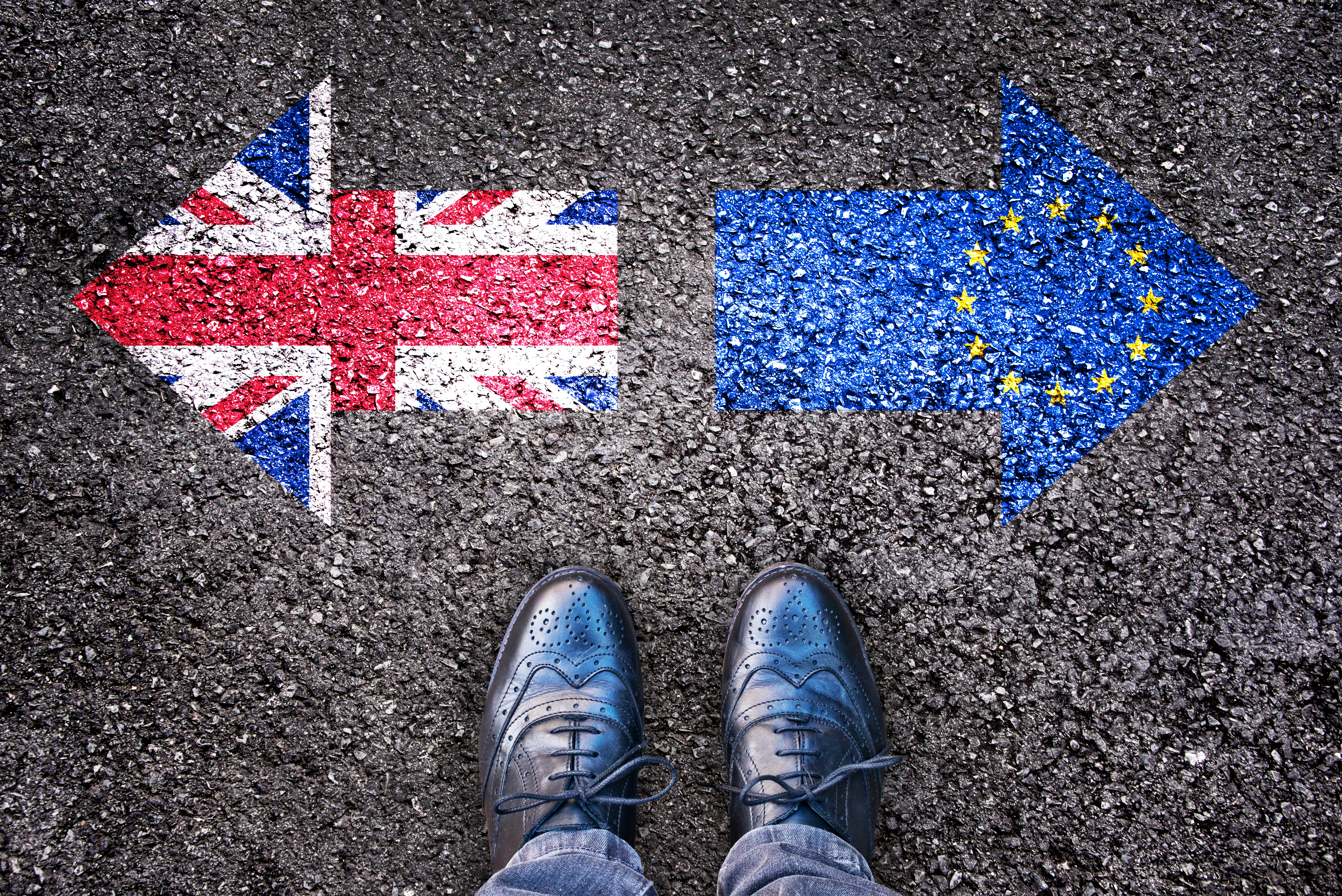Brexit, flags of the United Kingdom and the European Union on asphalt road with legs for feature on international law firms in Ireland