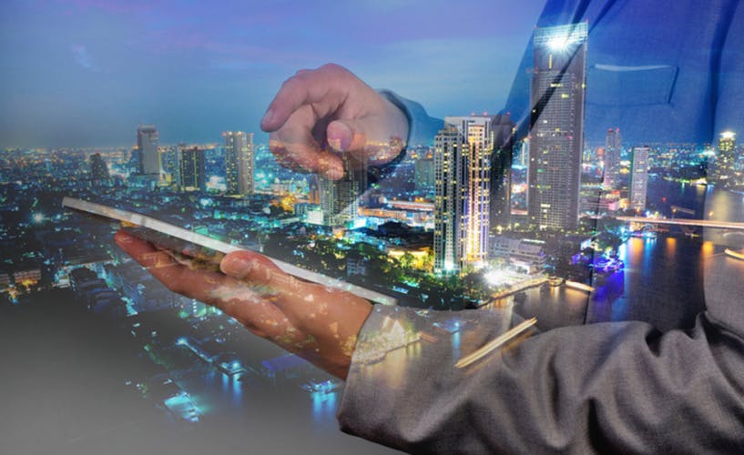 man in suit looking at laptop with city nightscape in the background